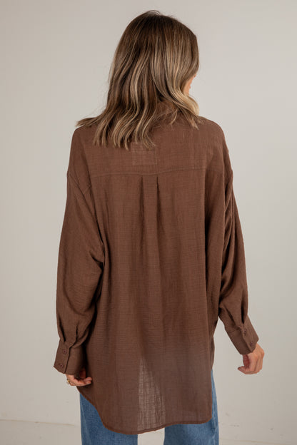 Brown long-sleeve shirt worn by a person on a plain background