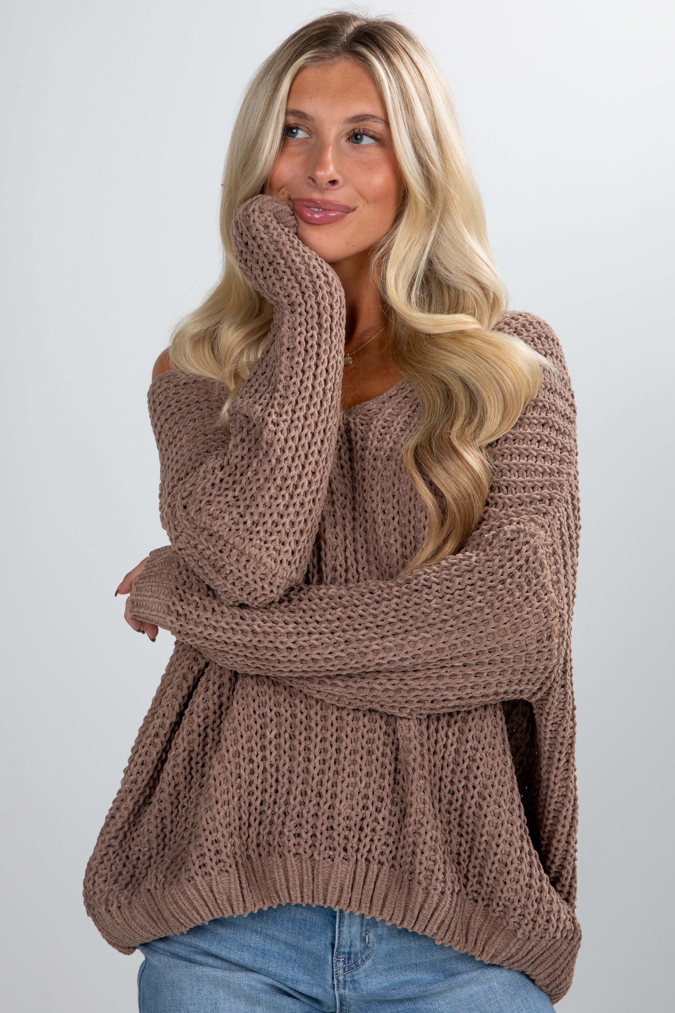 Woman wearing a brown knitted sweater against a plain background