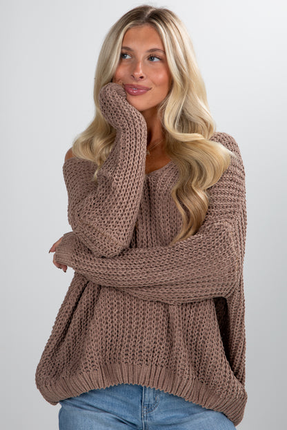 Woman wearing a brown knitted sweater against a plain background