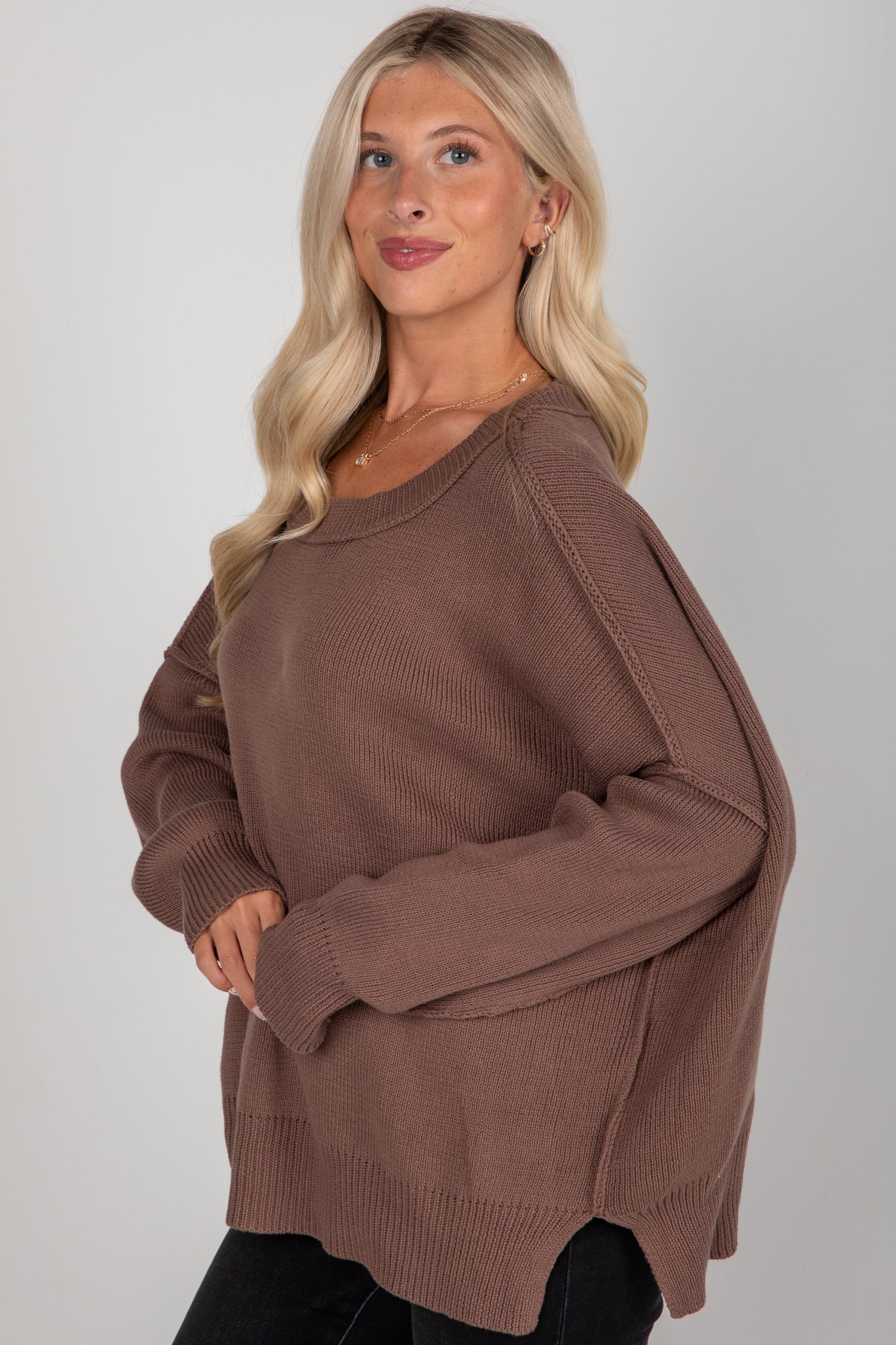 Woman wearing a brown sweater against a plain background