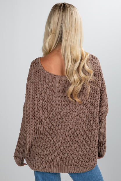 Person wearing a brown knitted sweater on a plain background