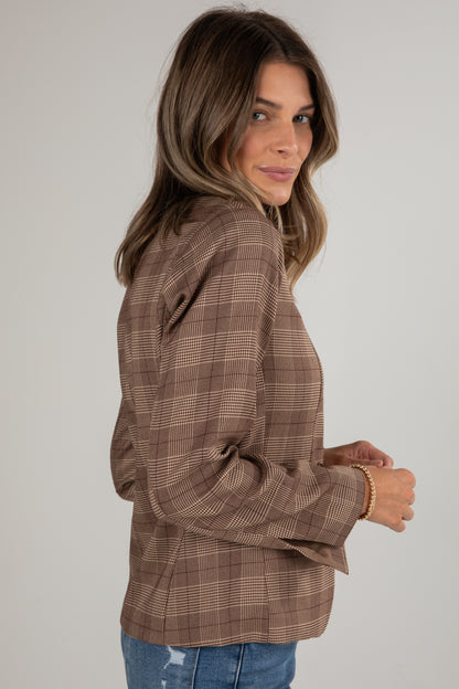 Woman wearing a brown plaid shirt against a plain background