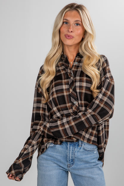 Woman wearing a plaid shirt and jeans against a plain background