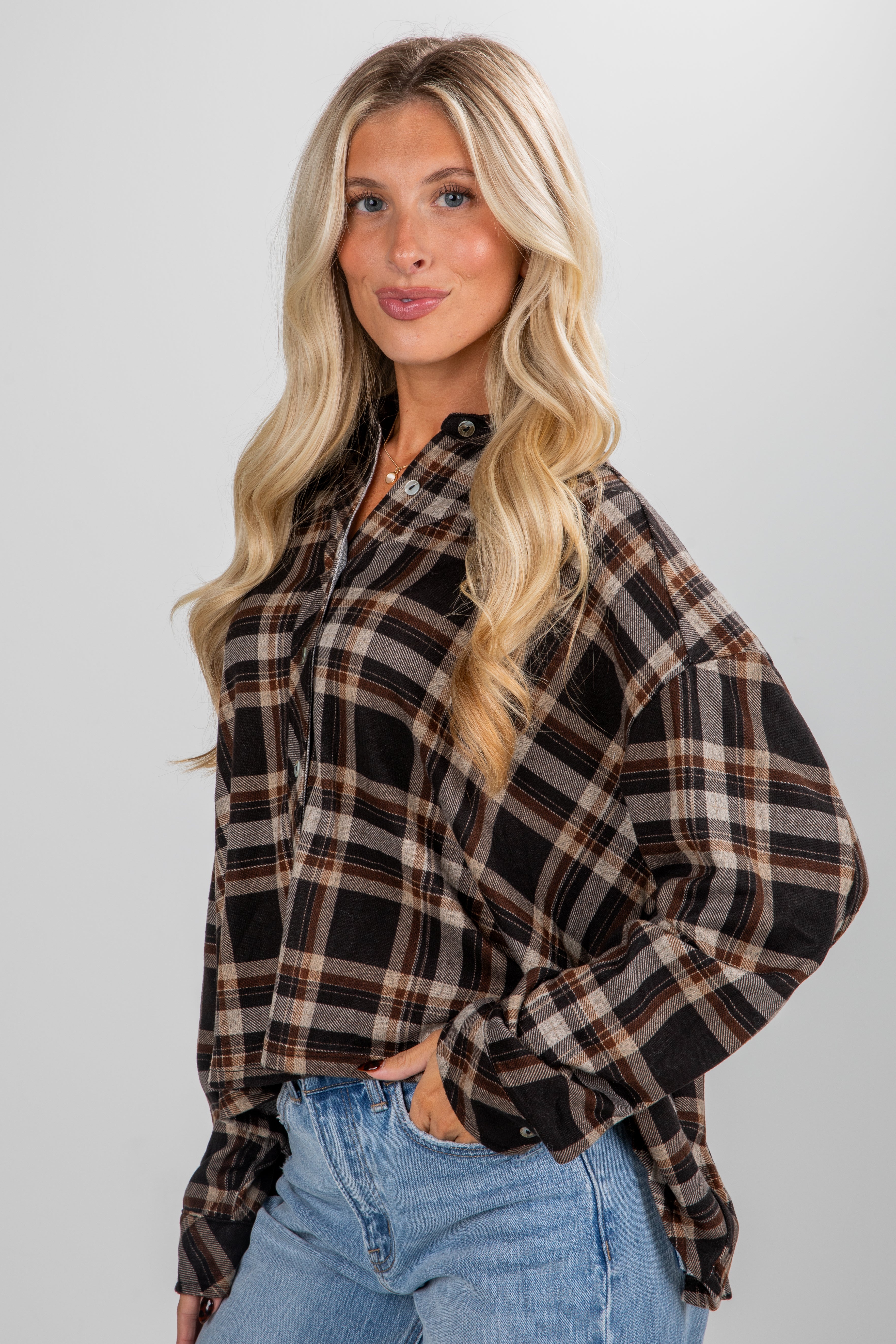 Woman wearing a plaid shirt and jeans against a plain background