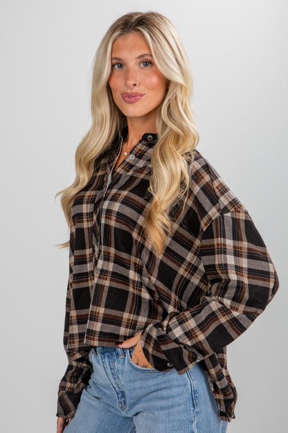 Woman wearing a plaid shirt and jeans against a plain background