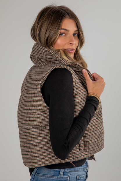 Woman wearing a plaid vest over a black long-sleeve shirt on a plain background