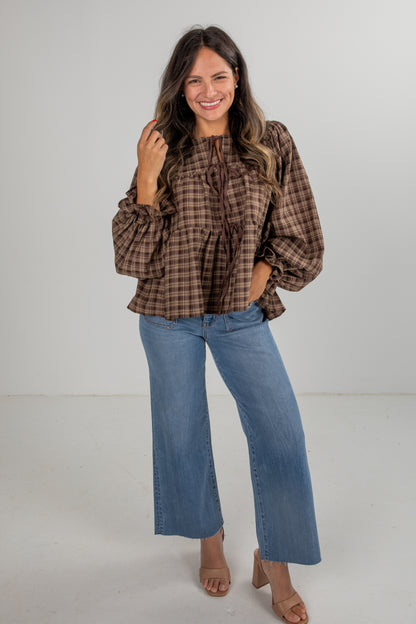 Woman wearing a plaid blouse and blue jeans on a white background