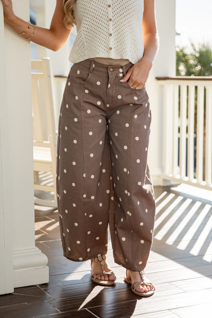 Person wearing brown polka dot pants on a wooden deck