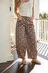 Woman wearing a white crochet top and brown polka dot pants on a porch.