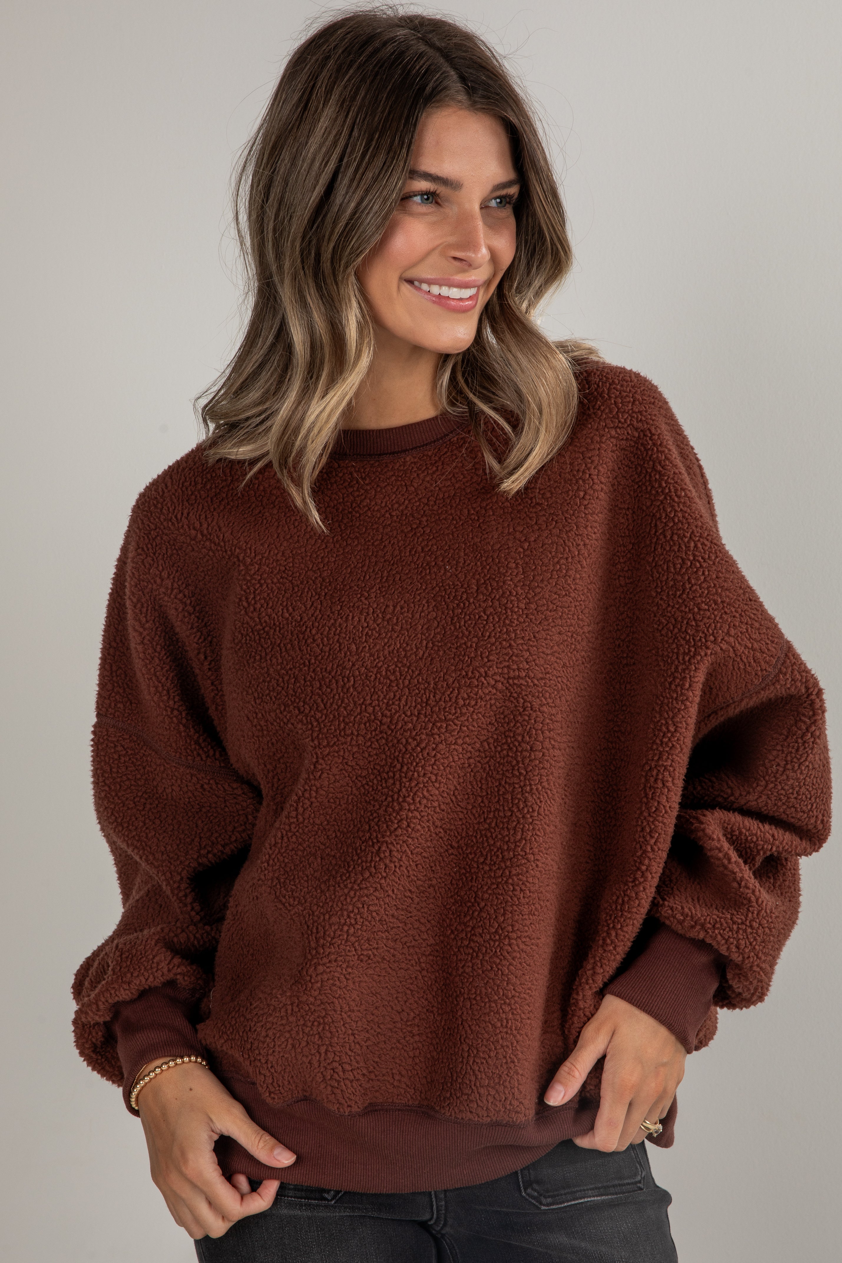 Woman wearing a brown sweater against a plain background