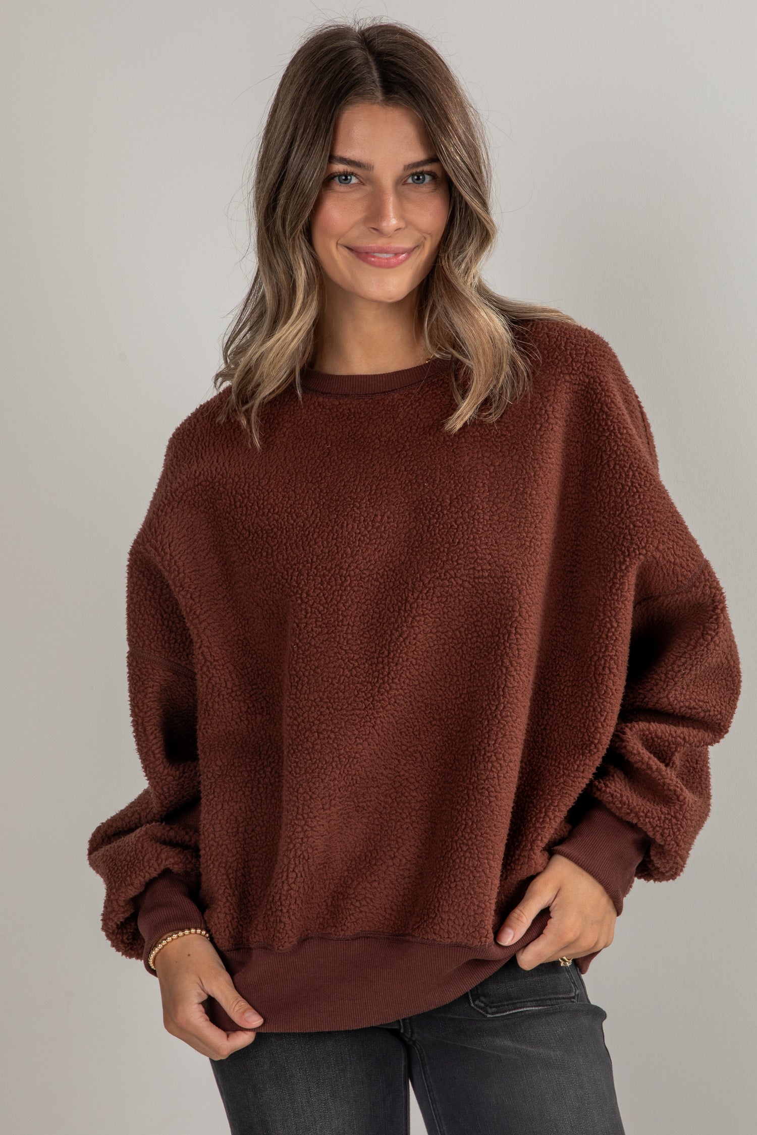 Woman wearing a brown sweater against a plain background
