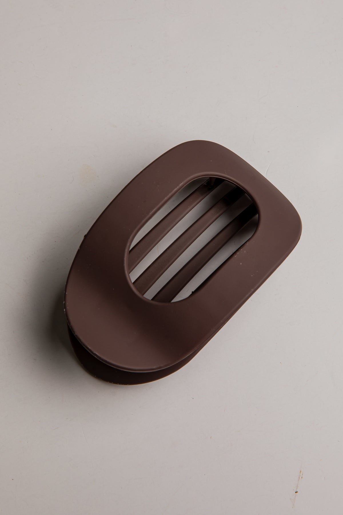 A dark brown silicone or rubber vent cover with a slotted oval cutout, shown on a plain light gray background.