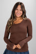 Woman wearing a brown long-sleeve top against a plain background
