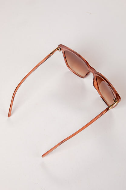 Sunglasses with brown frame and lenses on a light beige background