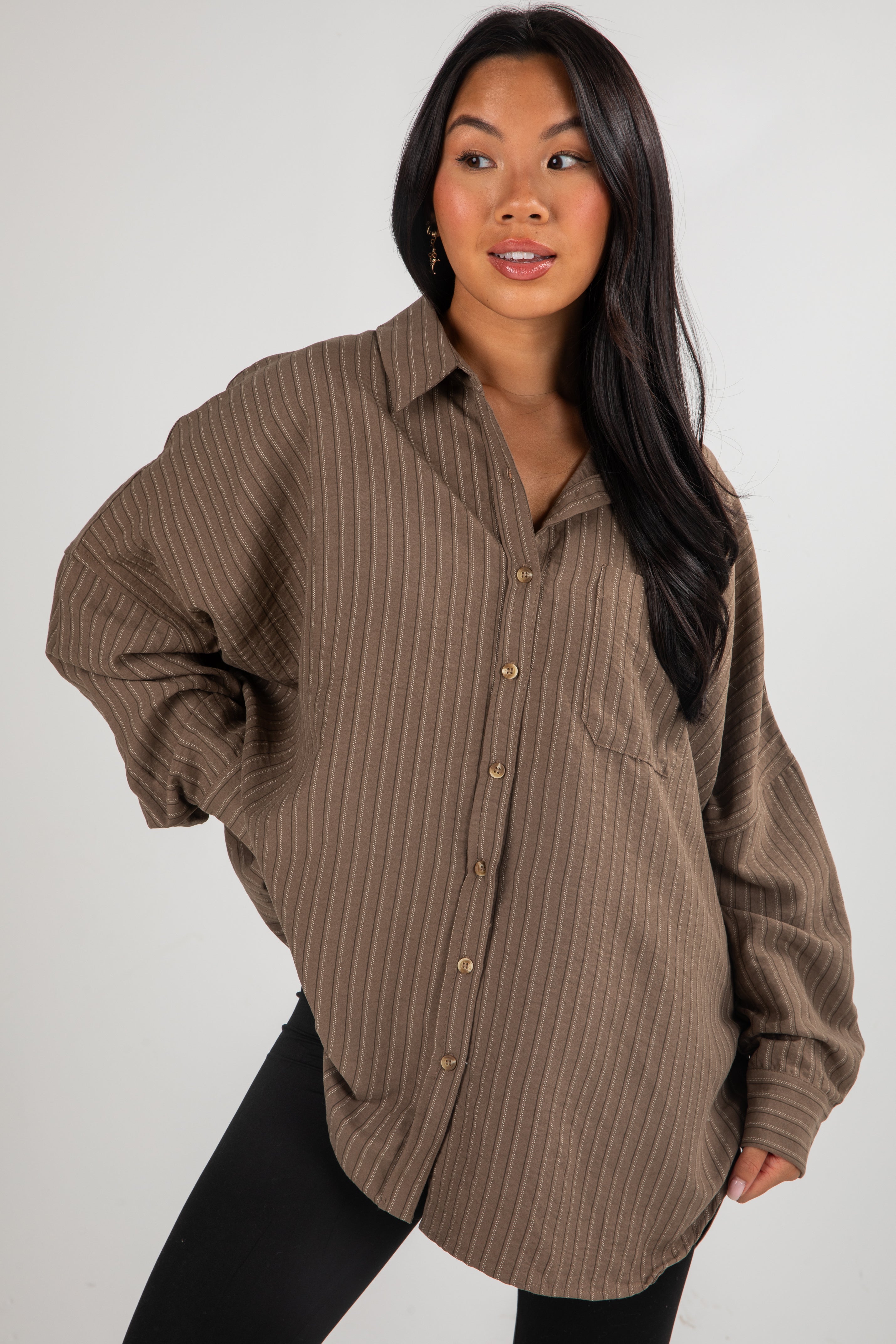 Woman wearing a brown striped shirt against a white background
