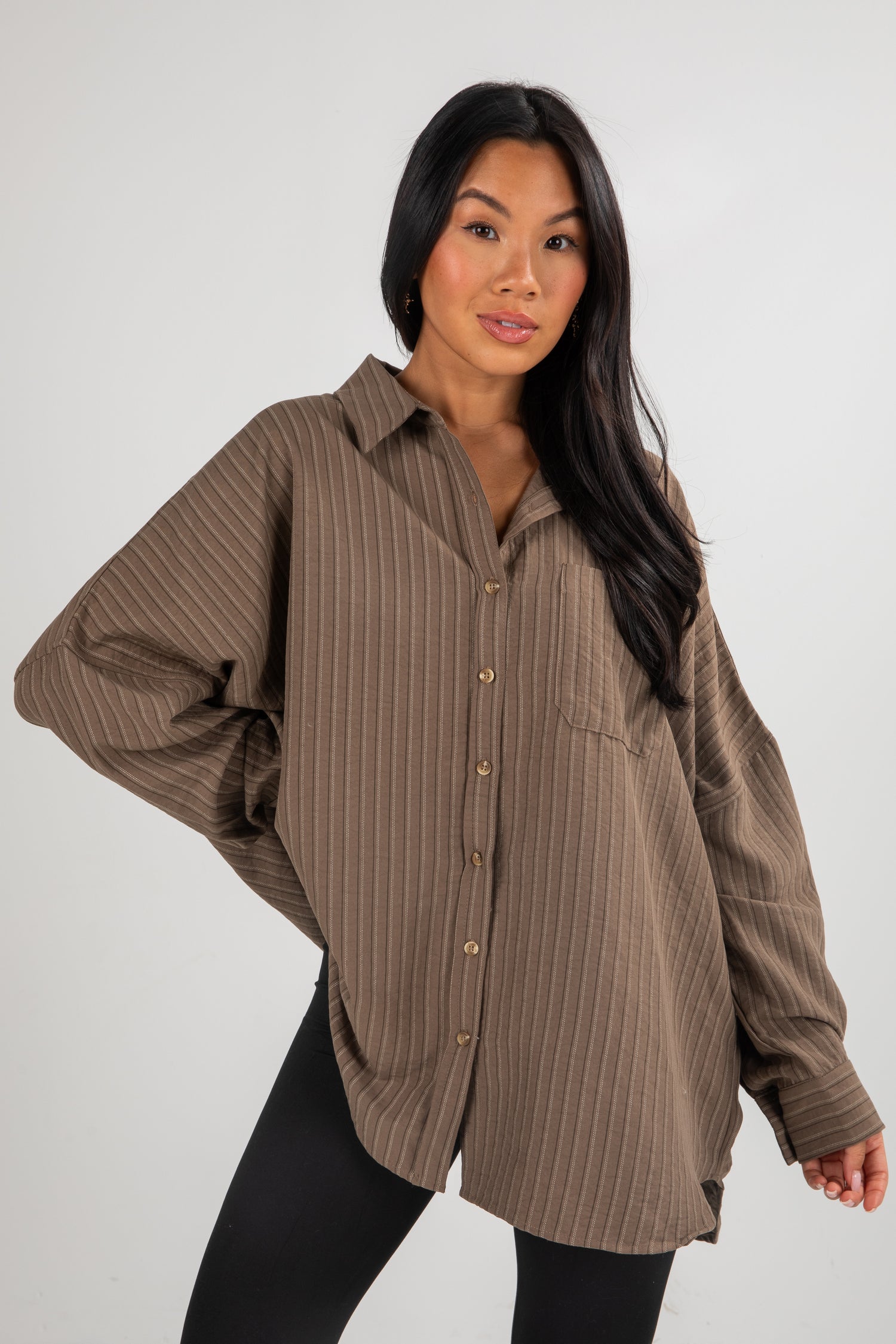Woman wearing a brown striped shirt against a white background