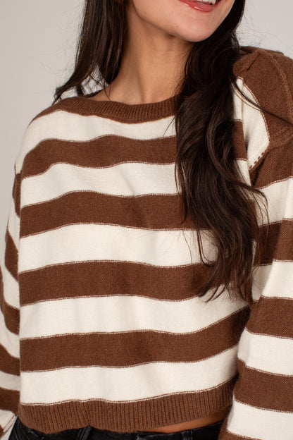 A close-up of a woman wearing a brown and cream striped knit sweater, showing the texture of the fabric and the horizontal stripe pattern.