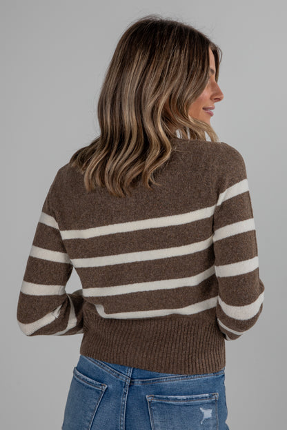 Woman wearing a brown and white striped sweater against a gray background