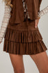 Brown suede skirt worn by a person on a plain background