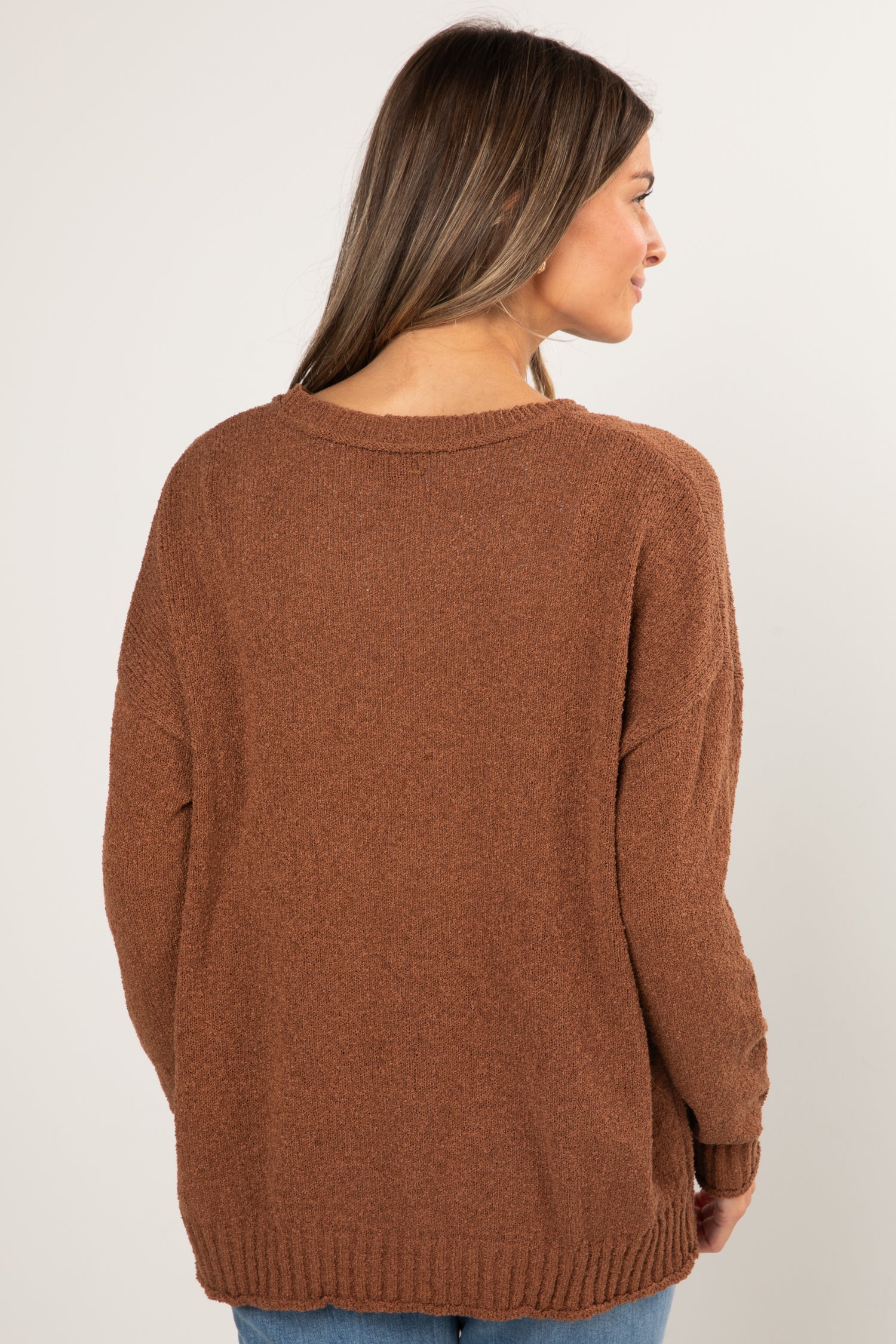 Woman wearing a brown sweater against a white background