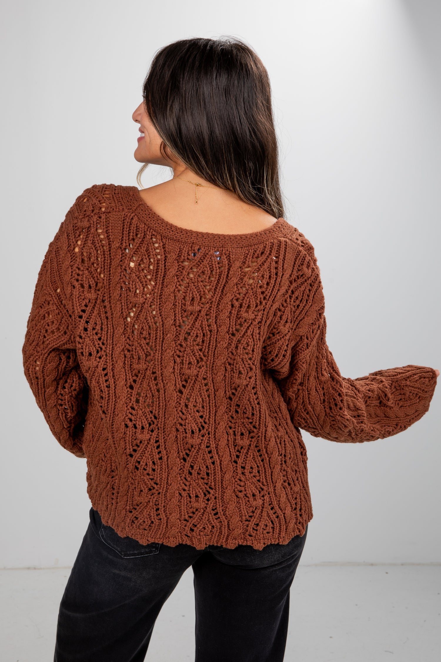 Woman wearing a brown knitted sweater against a white background