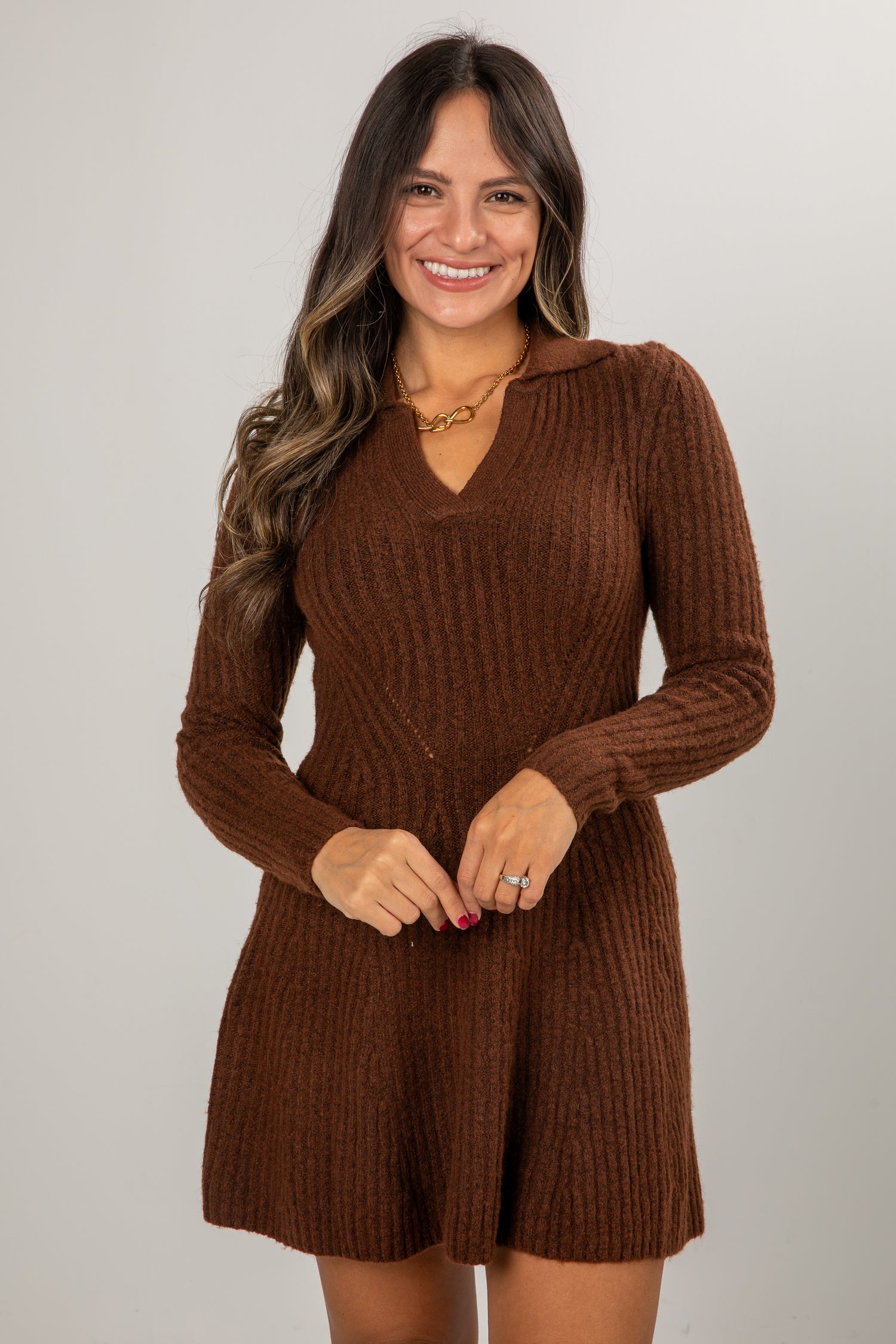 Woman wearing a brown ribbed knit dress against a plain background