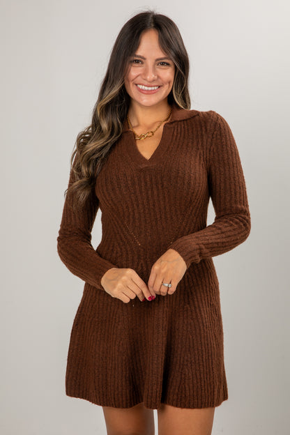Woman wearing a brown ribbed knit dress against a plain background