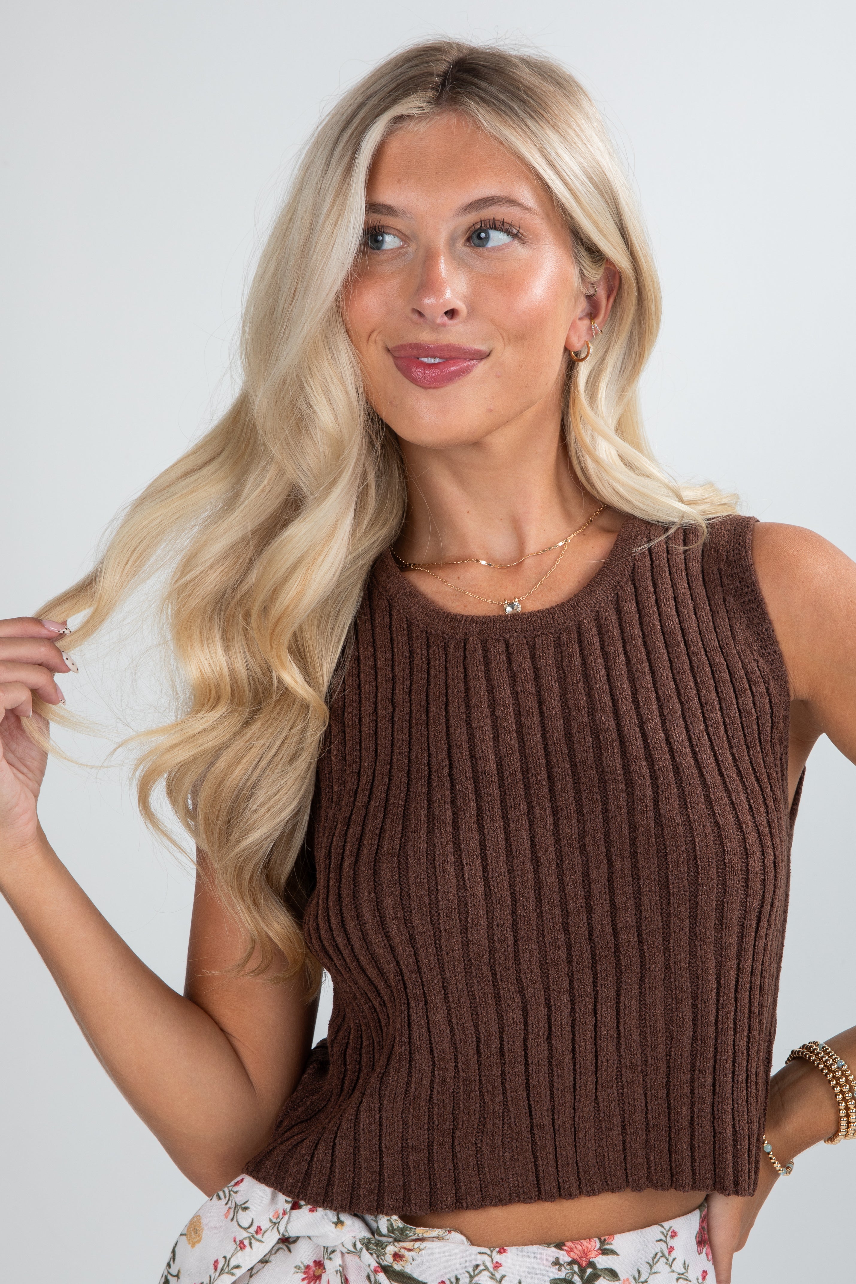 Woman wearing a brown ribbed tank top against a plain background