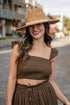 Woman wearing a brown hat and matching outfit on a street.
