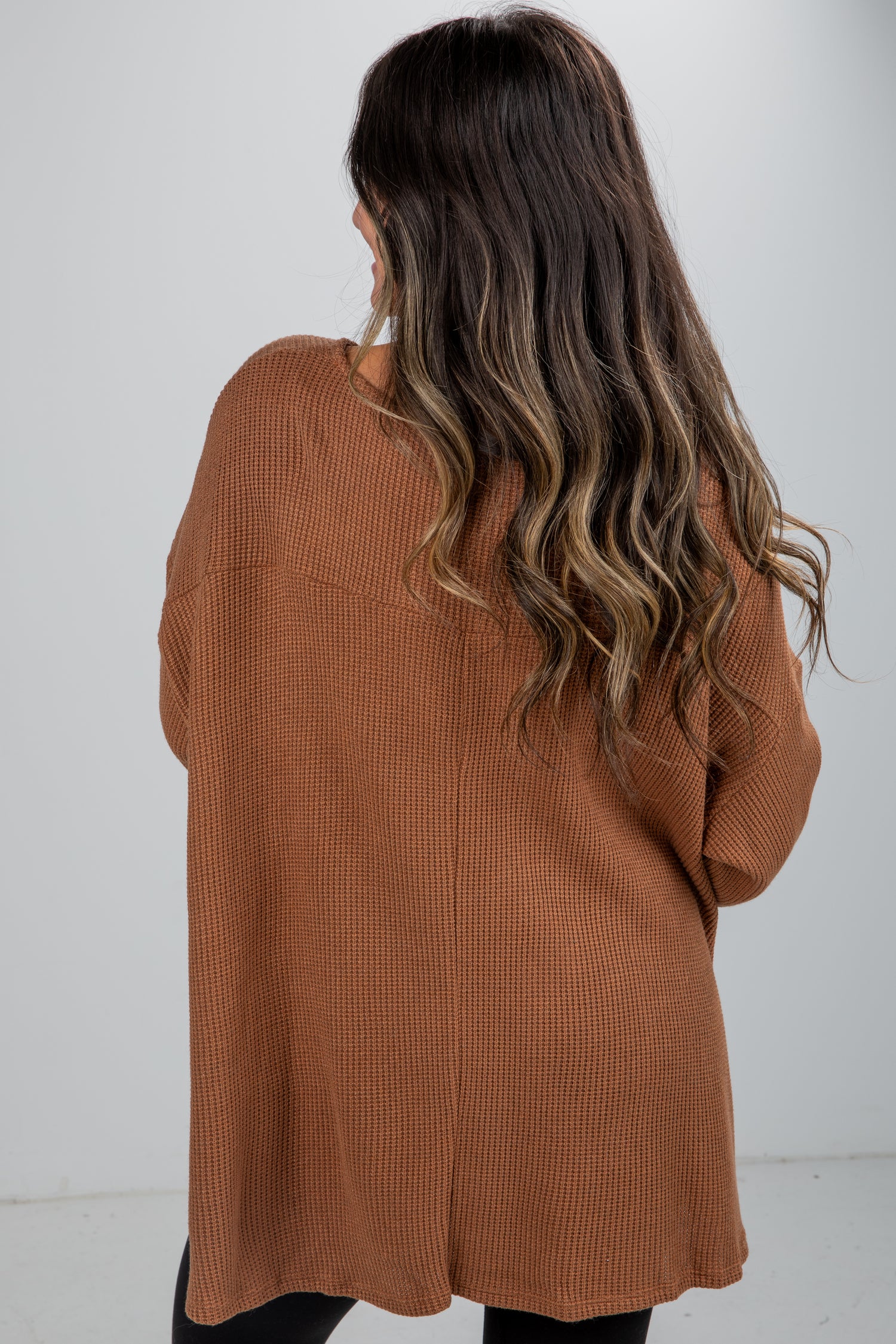 Person wearing a brown cardigan against a white background