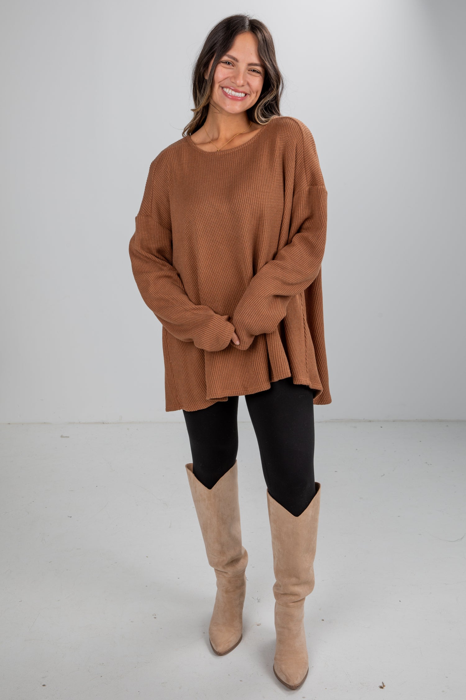 Woman wearing a brown sweater and beige knee-high boots on a white background
