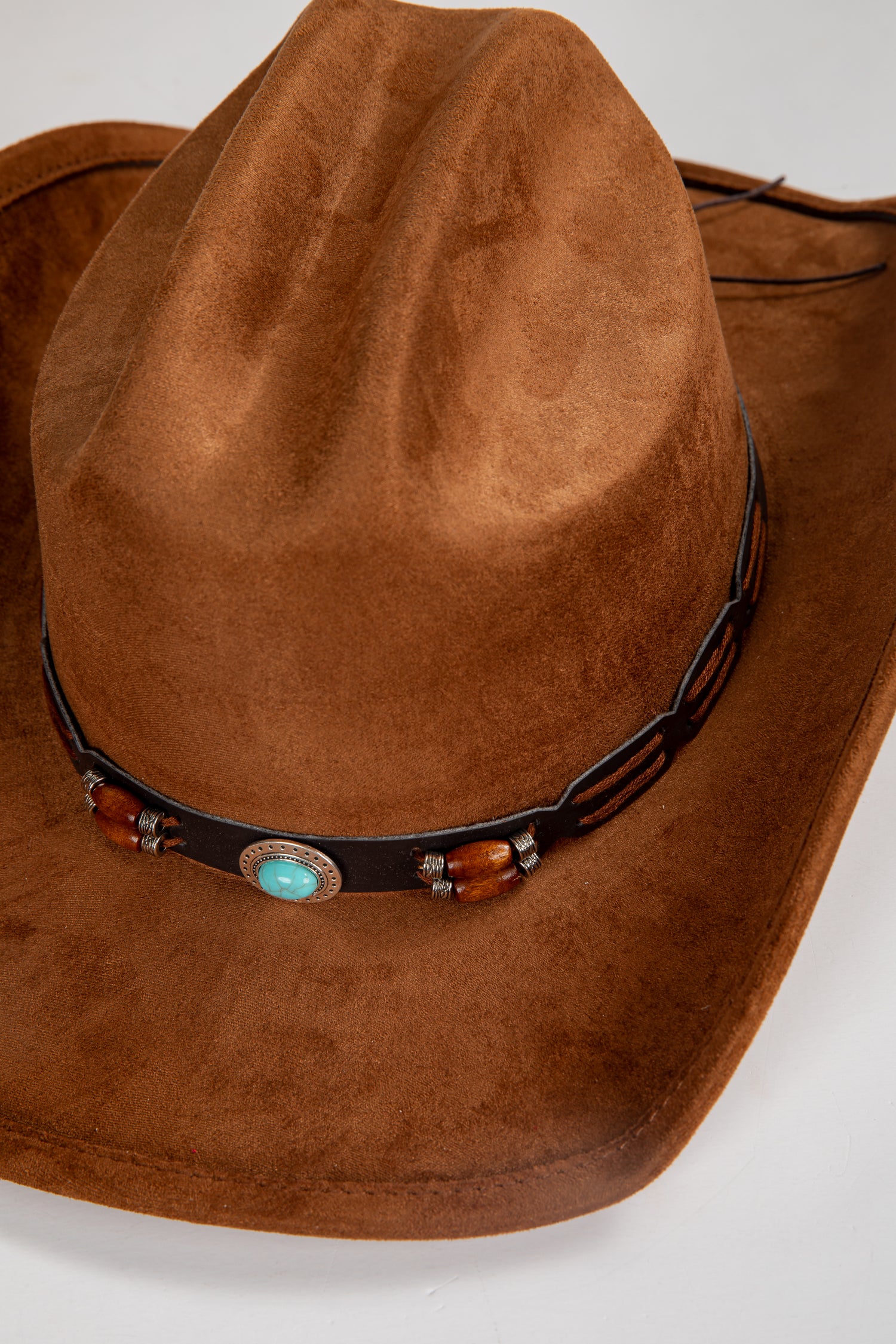Brown cowboy hat with decorative band featuring turquoise stone and wooden beads on a white background