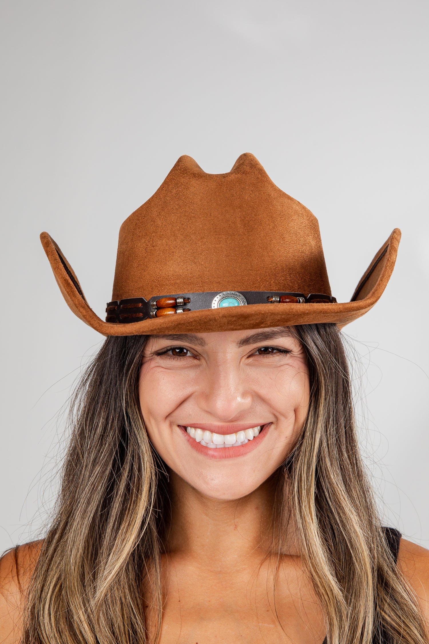 Woman wearing a brown cowboy hat against a plain background