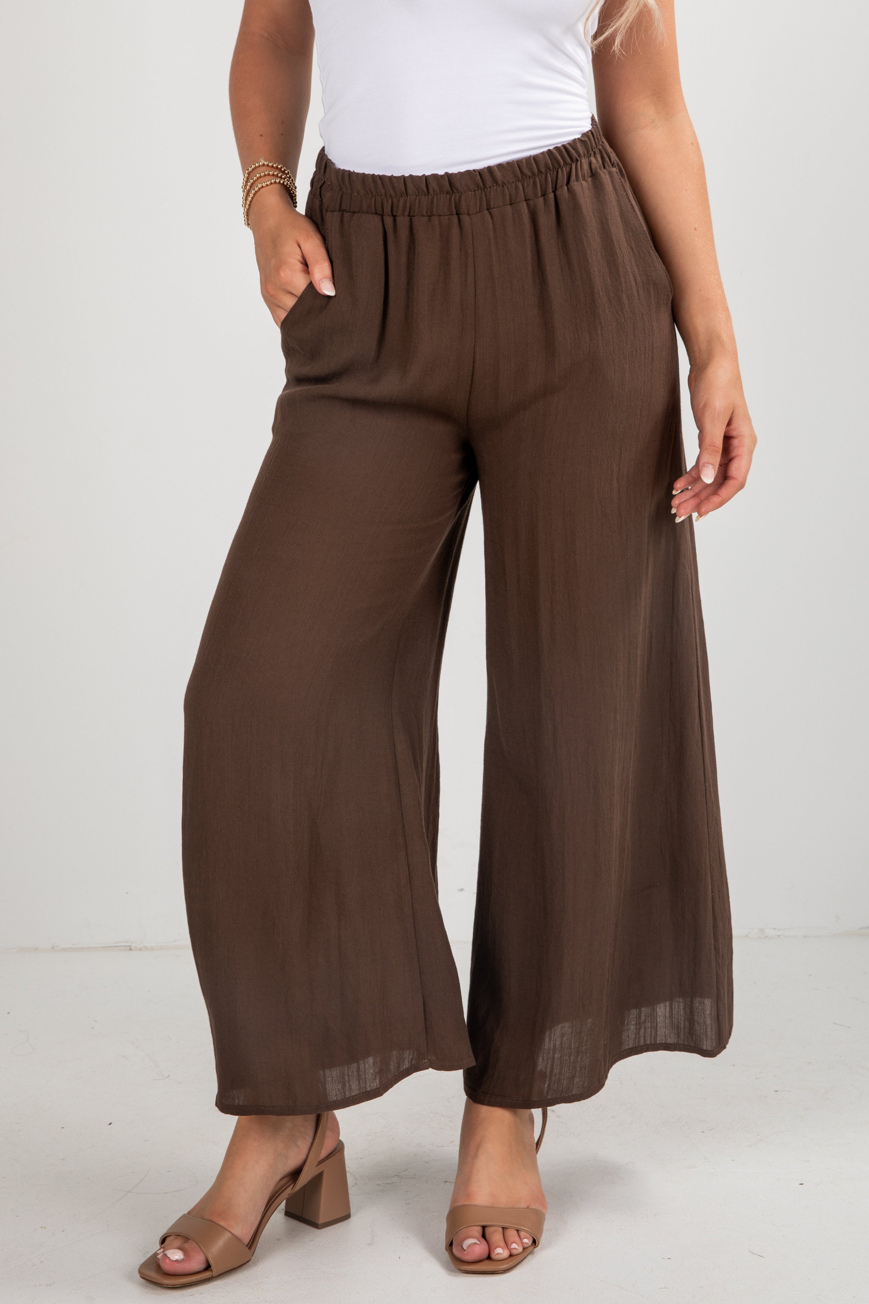 Brown wide-leg pants worn by a person on a white background