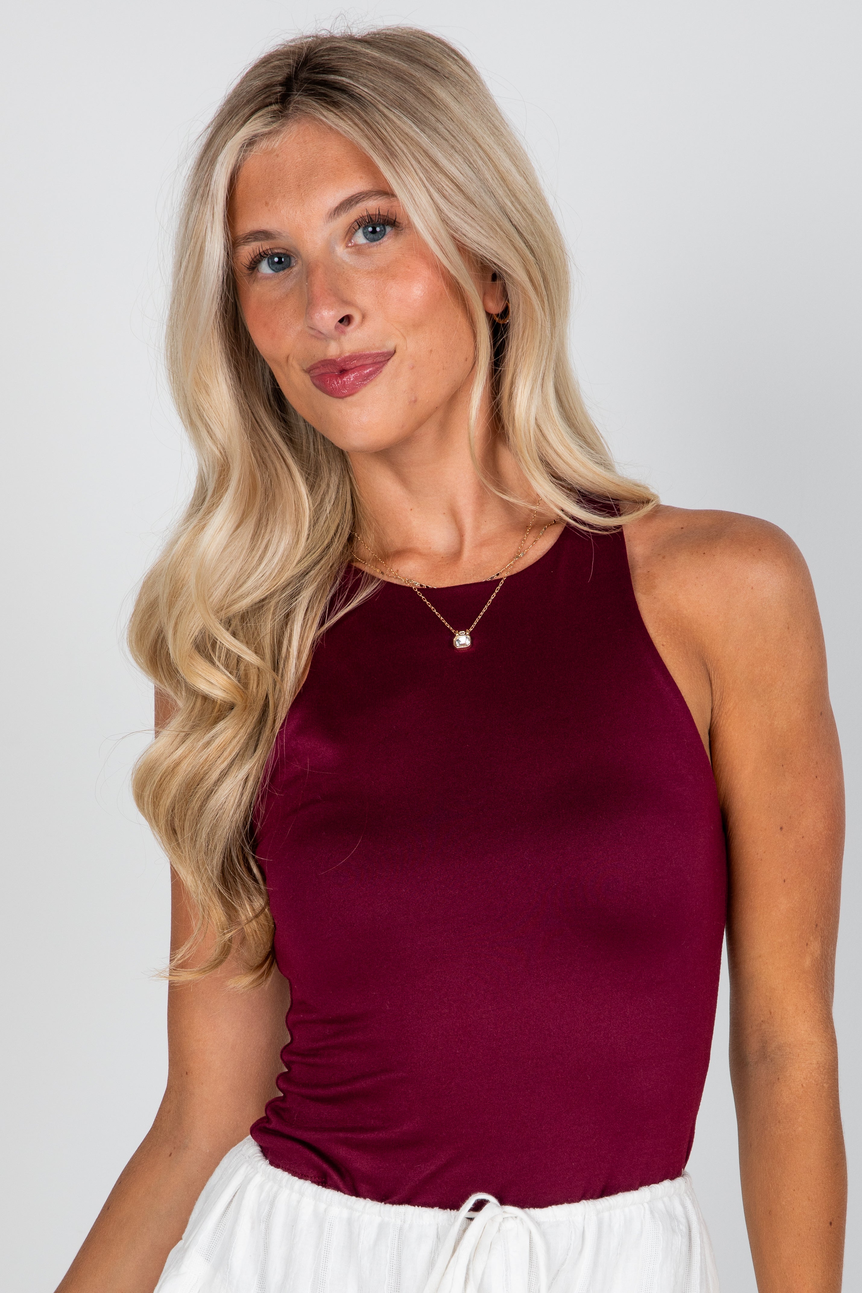 Woman wearing a burgundy tank top against a plain background