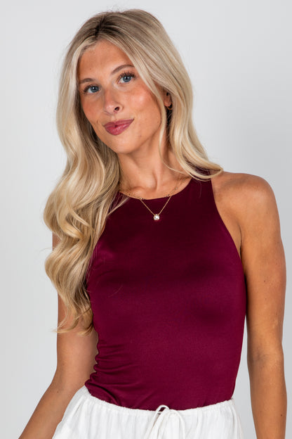 Woman wearing a burgundy tank top against a plain background