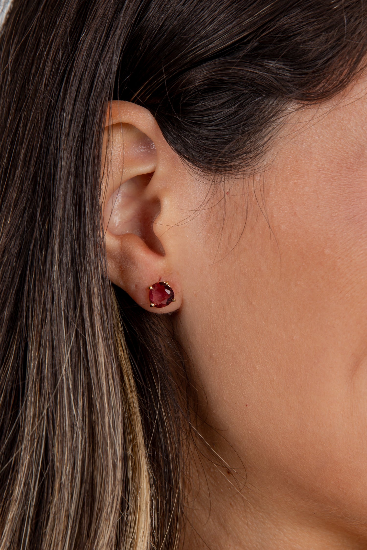 Close-up of an ear wearing a red earring with hair partially covering the face.