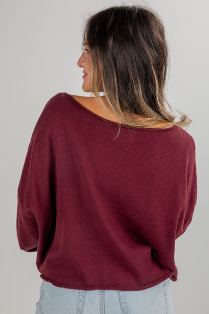 Woman wearing a burgundy sweater against a plain background