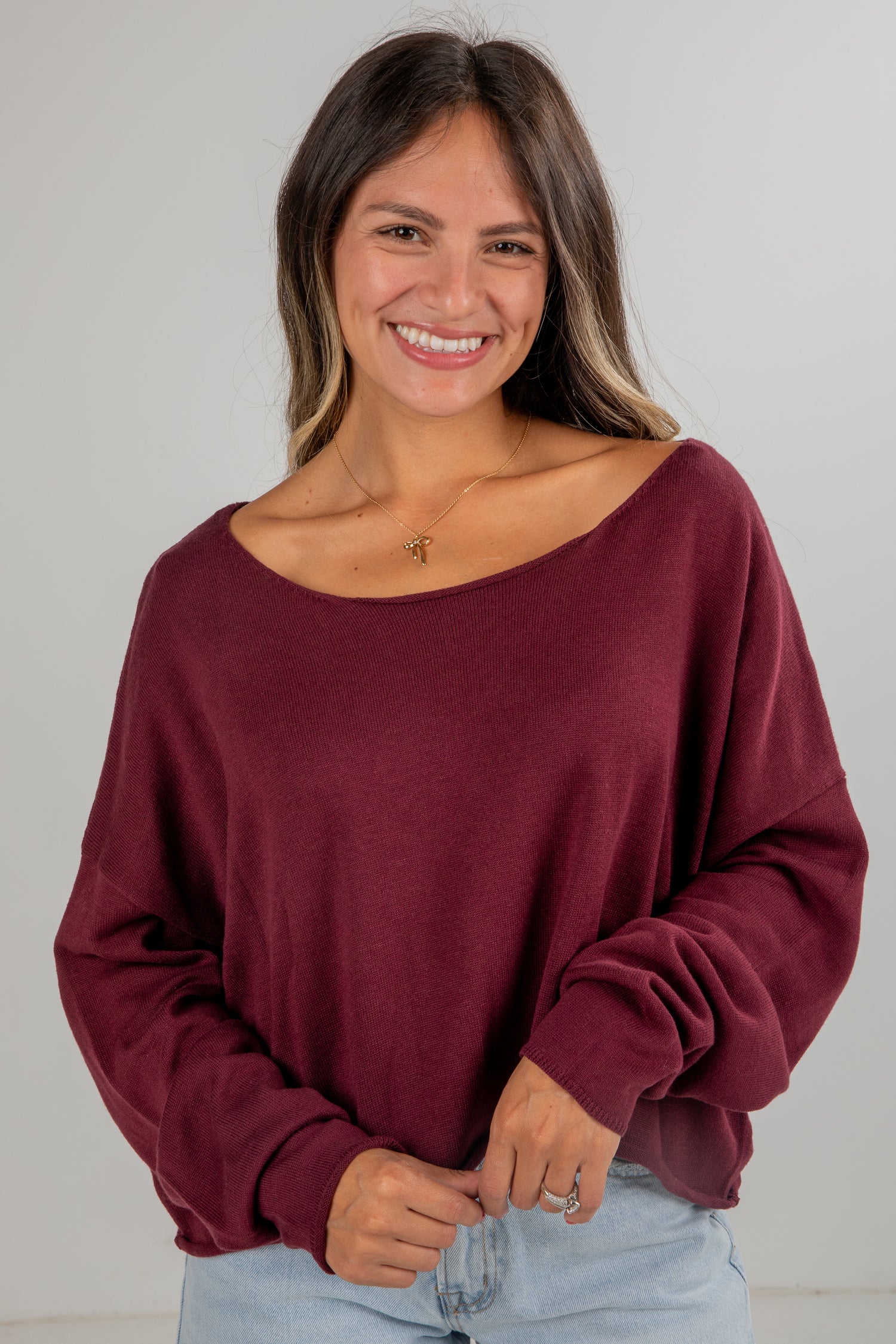 Woman wearing a burgundy oversized sweater against a plain background