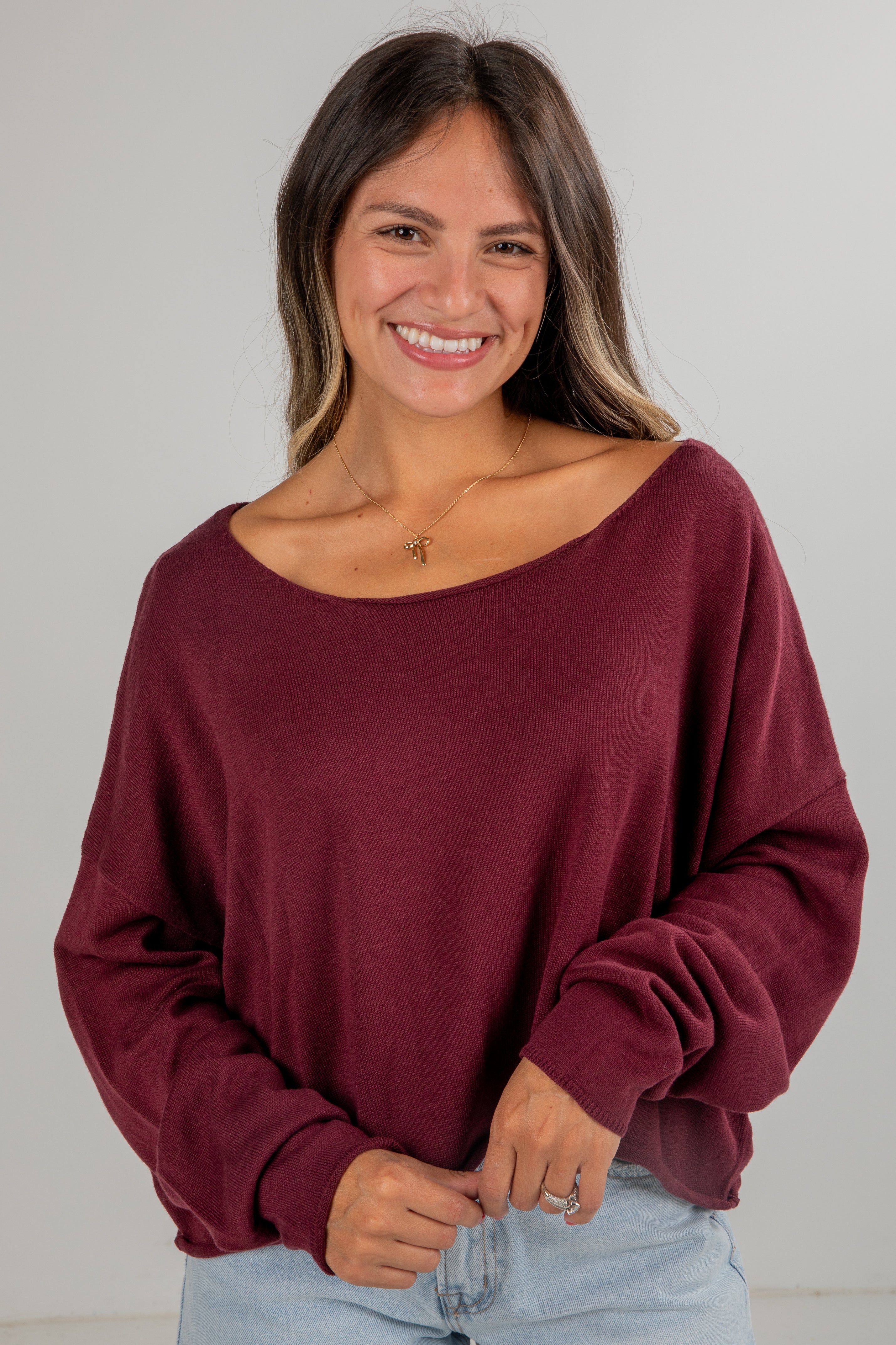 Woman wearing a burgundy oversized sweater against a plain background