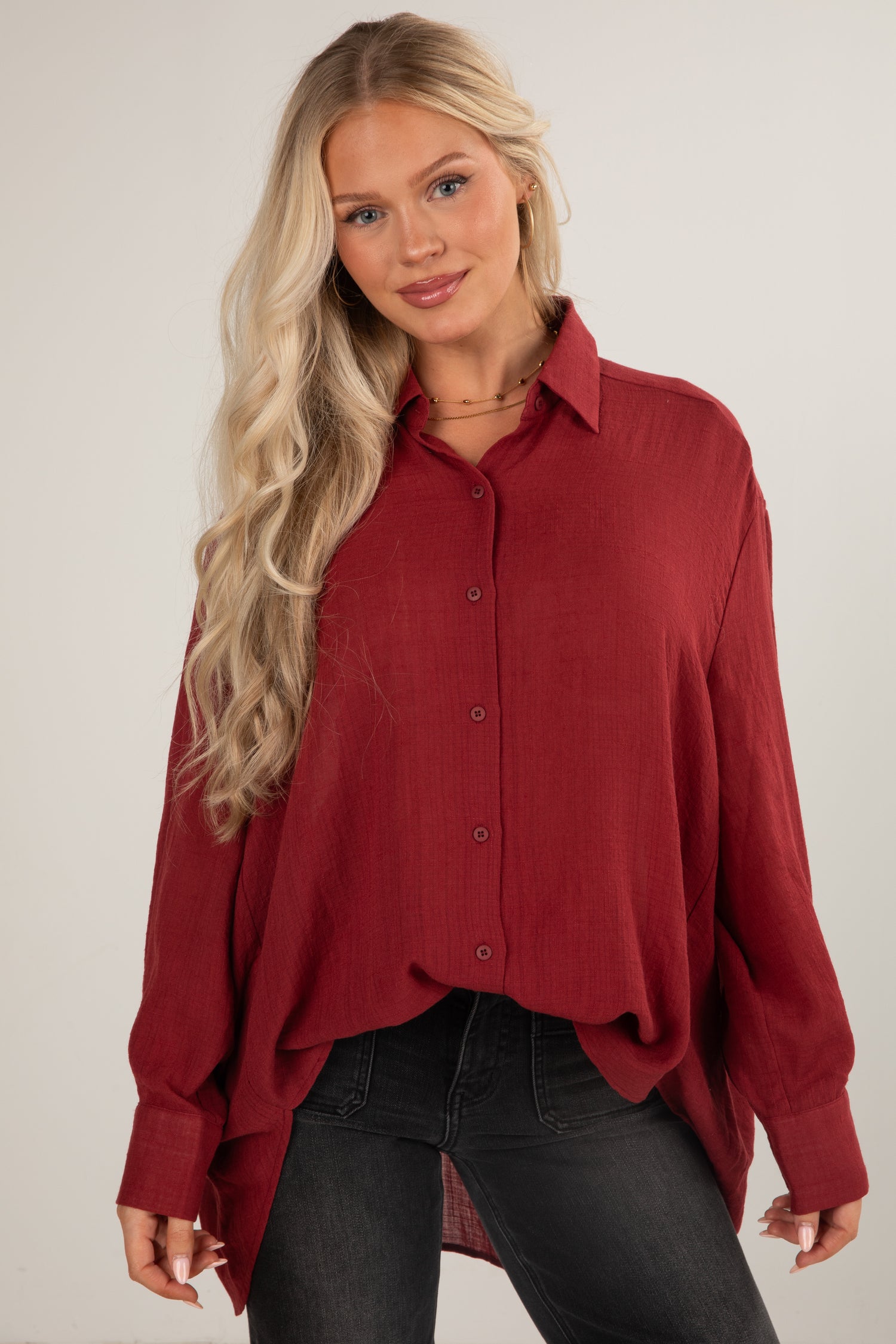 Woman wearing a red button-up shirt against a plain background