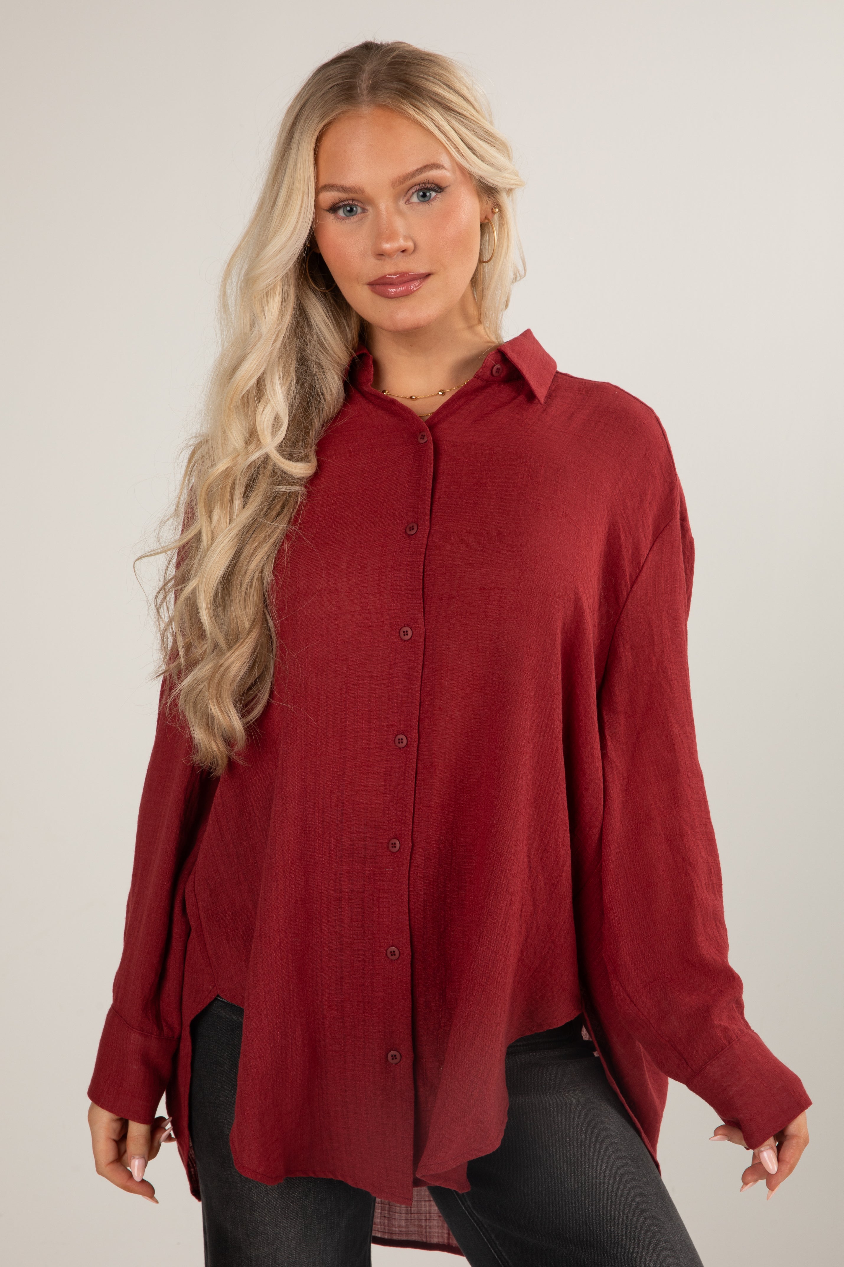 Woman wearing a red button-up shirt against a plain background
