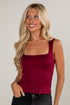 Woman wearing a burgundy tank top against a plain background