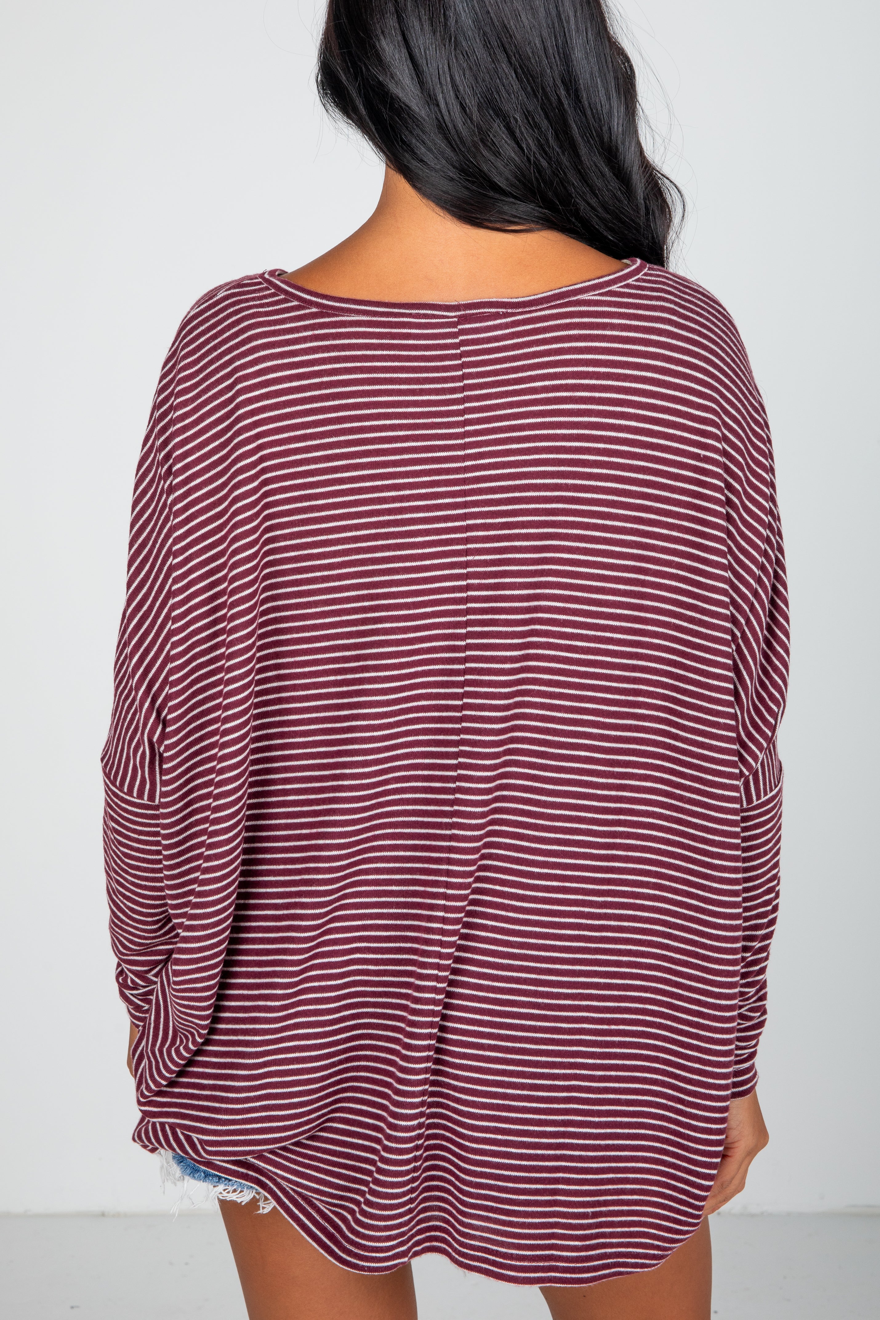 Maroon and white striped long-sleeve top worn by a person on a plain background