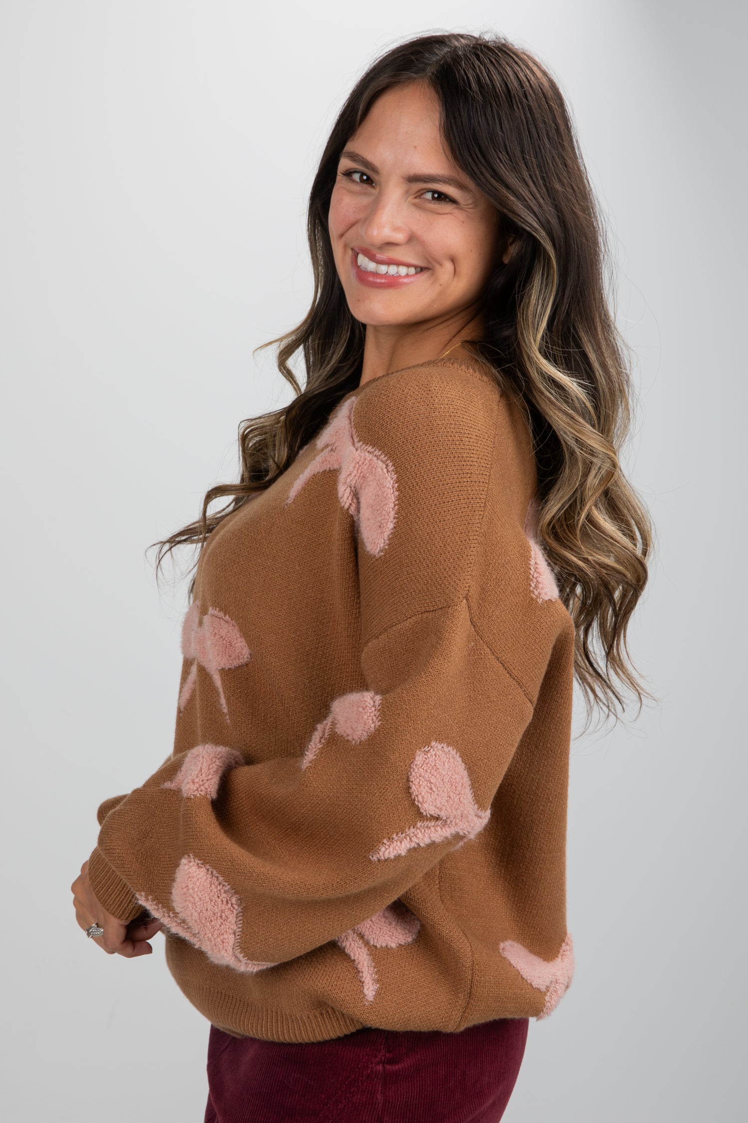 Woman wearing a brown sweater with flamingo patterns on a plain background