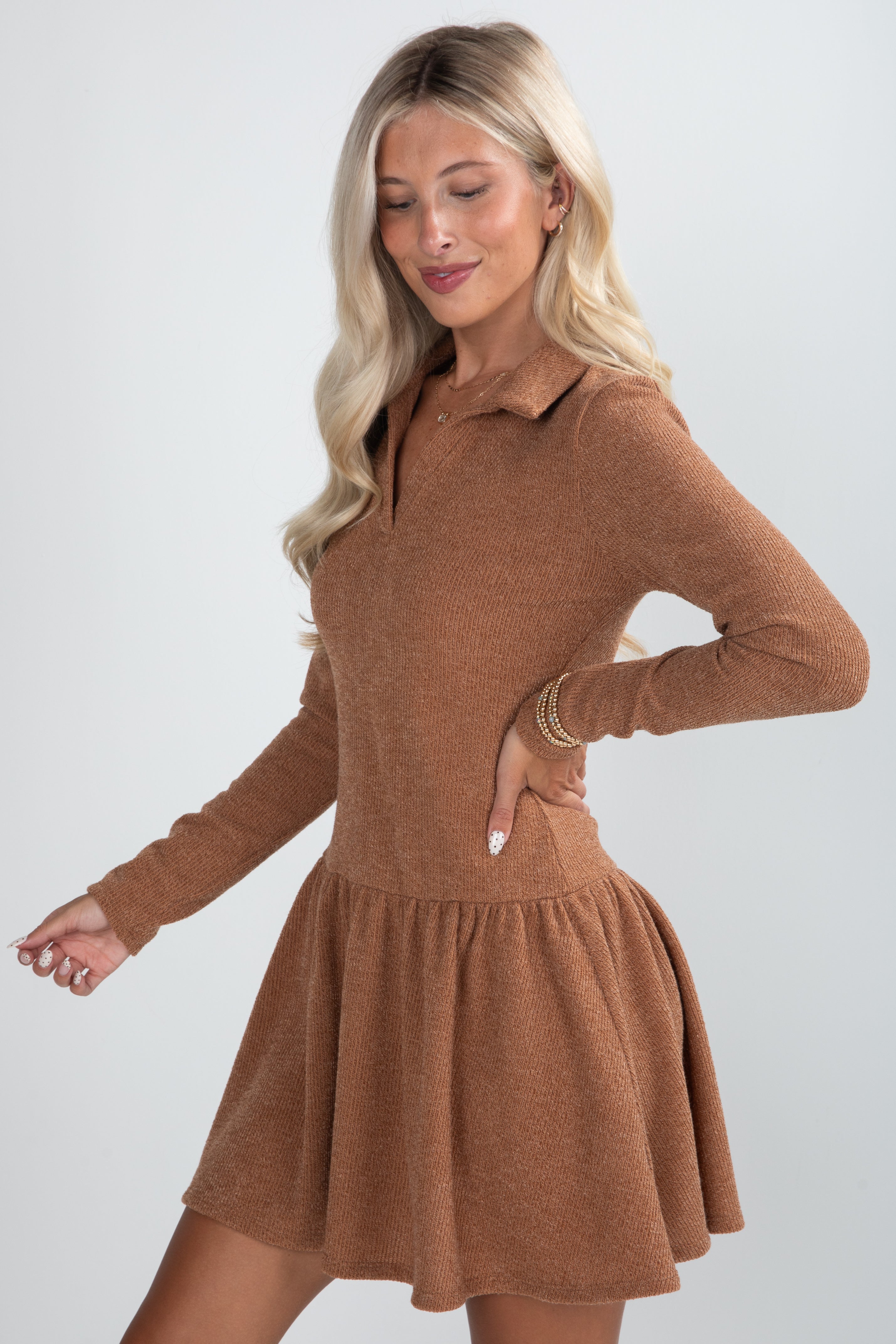 Woman wearing a brown dress with long sleeves on a white background