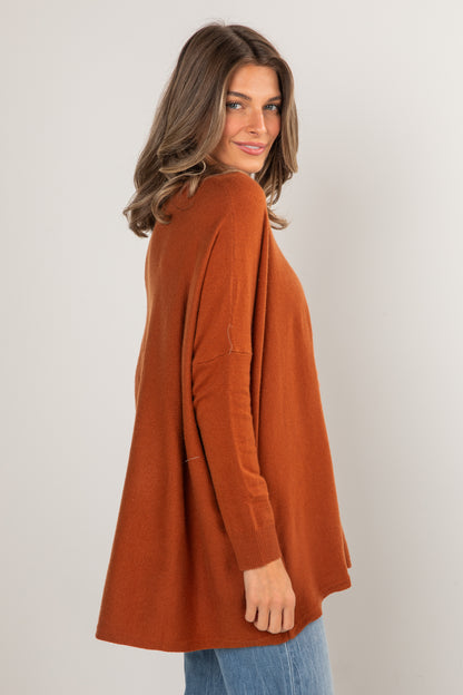Woman wearing a rust-colored cardigan against a plain background