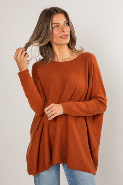 Woman wearing a rust-colored sweater against a plain background