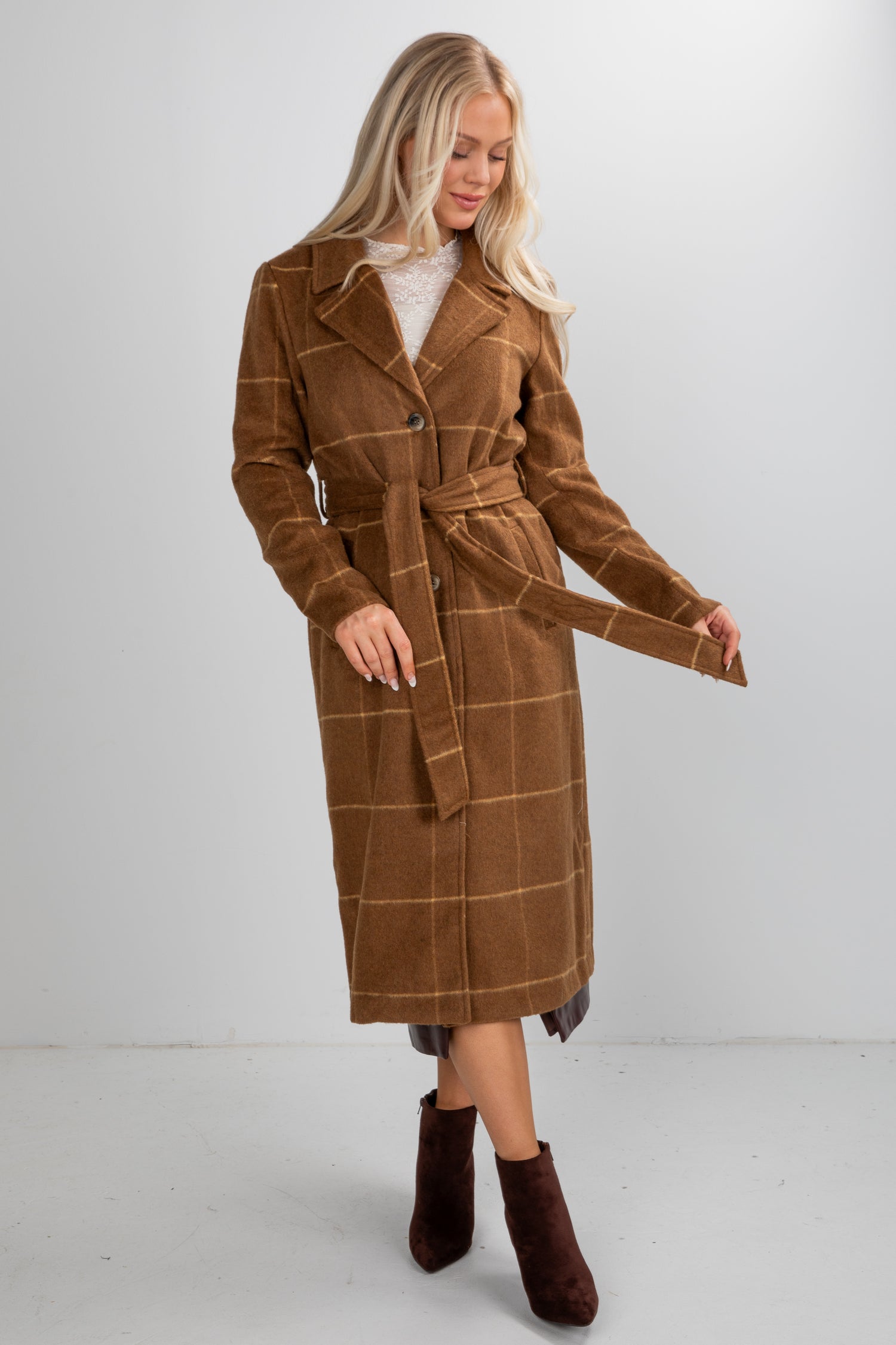 Woman wearing a brown plaid coat on a white background