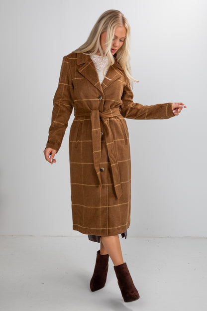 Woman wearing a brown plaid coat on a white background